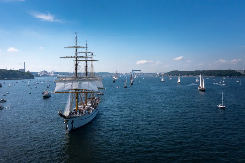 Großsegler Gorch Fock mit Gästen an Deck bei der Windjammerparade zur Kieler Woche, ringsum zahlreiche Segelboote